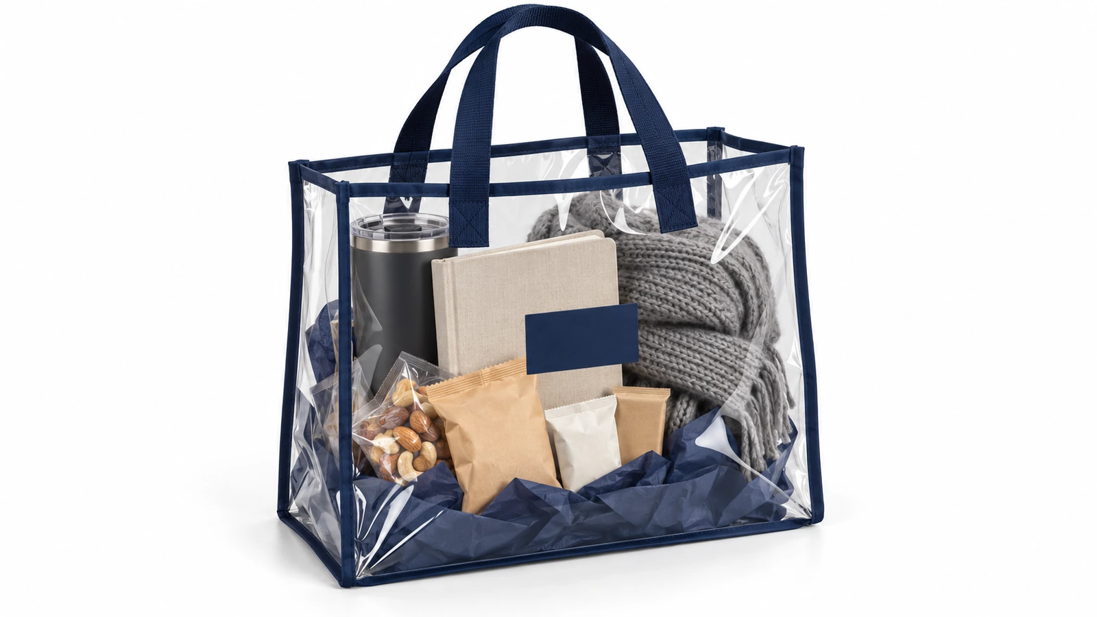 Tote bag PVC bening dengan list tepi biru tua berisi paket hadiah korporat berupa tumbler, buku catatan, camilan, dan syal terlipat, semuanya terlihat dari balik tas
