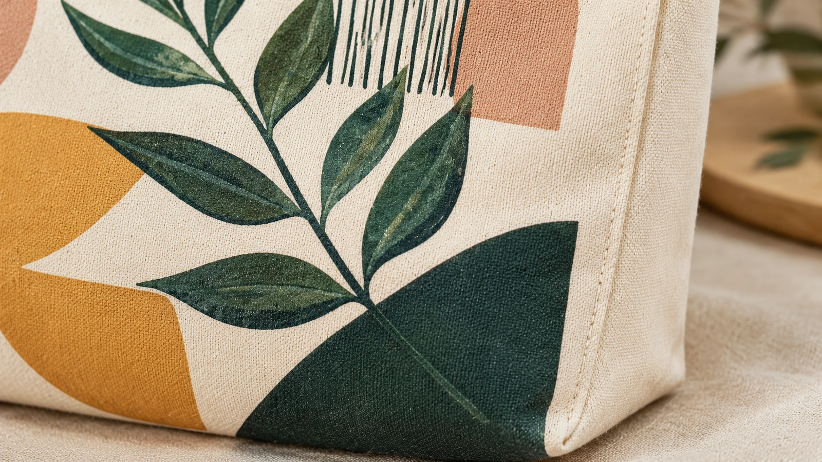 Close-up tas tote kanvas bercetak yang menampilkan desain daun dan lipatan samping (gusset) yang dijahit