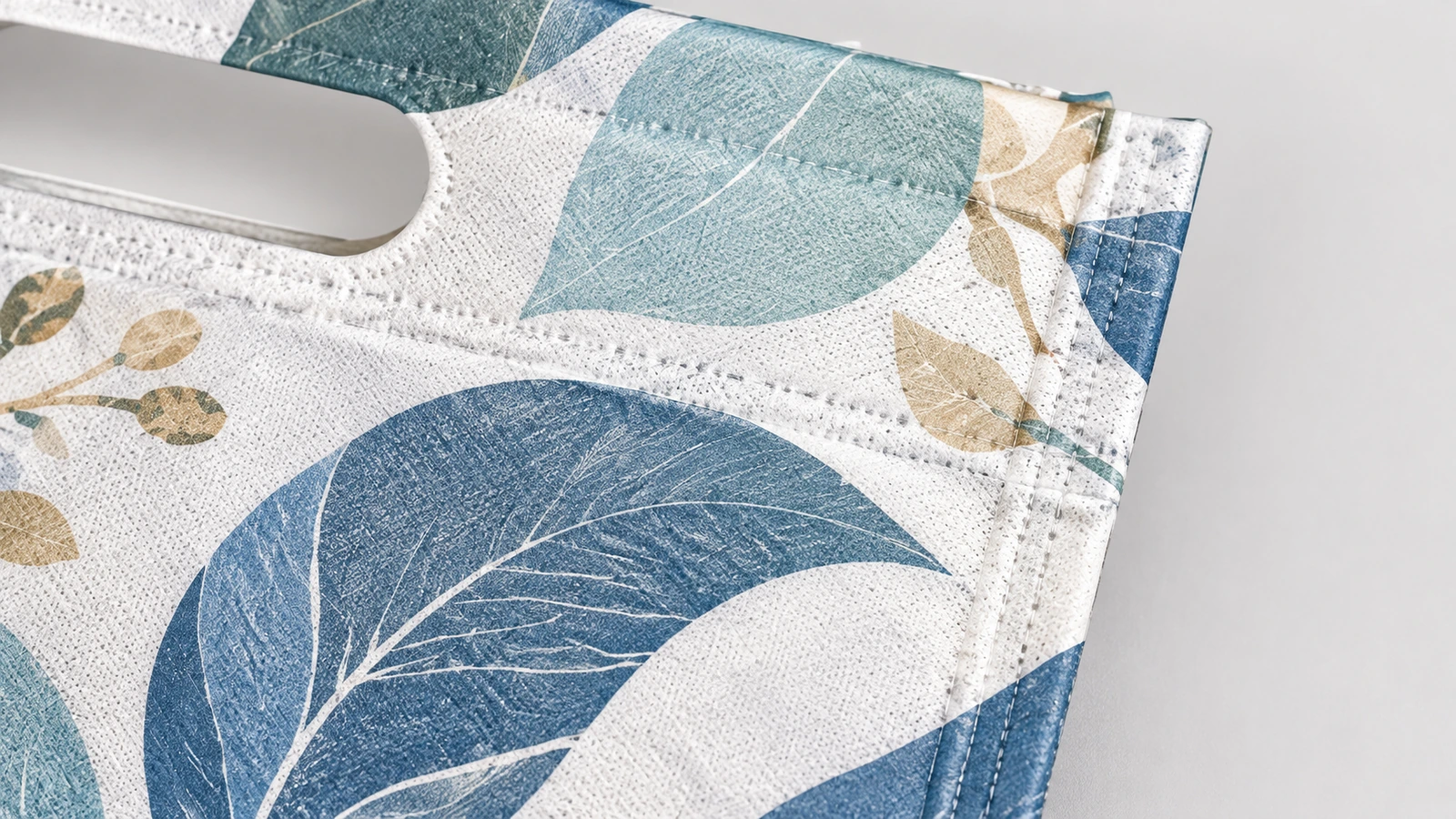 Close-up permukaan tas bermotif daun dan bukaan pegangan hasil die-cut